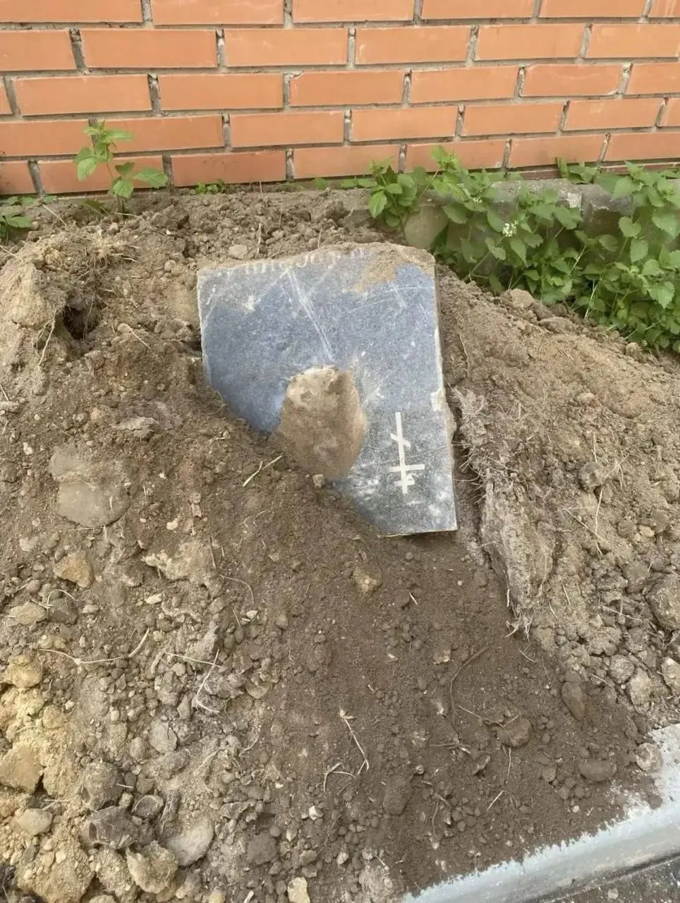Возле детской площадки обнаружили куски памятников, облицовочную плитку и части истлевшей ткани в завезённом грунте; местные власти и надзорные органы пока не прокомментировали ситуацию.